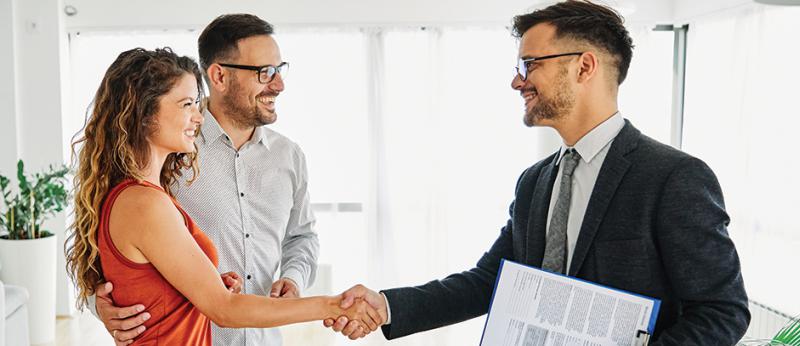 Photo of a male realtor shaking the hands of a couple