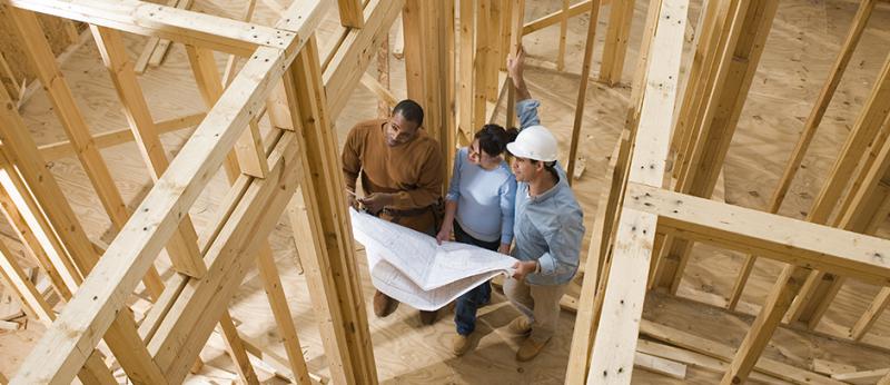 photo from above of a couple looking at blueprints in a new home