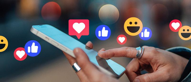 photo illustration of hands holding a phone with like emojis floating above
