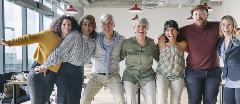 Photo of team of business people with arms around each others shoulders