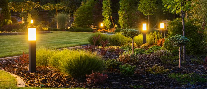Modern Backyard Outdoor LED Lighting Systems - stock photo  Panoramic Photo of LED Light Posts Illuminated Backyard Garden During Night Hours. Modern Backyard Outdoor Lighting Systems.