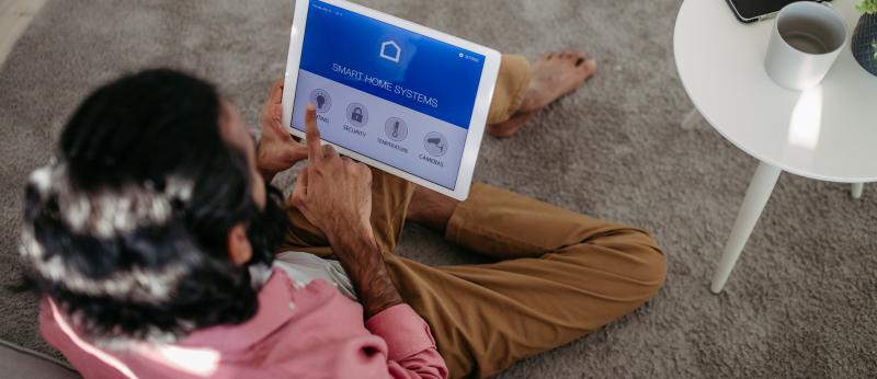 Man adjusting household functions, lighting, security cameras, door locks and thermostat or heating settings in the smart home system. - stock photo