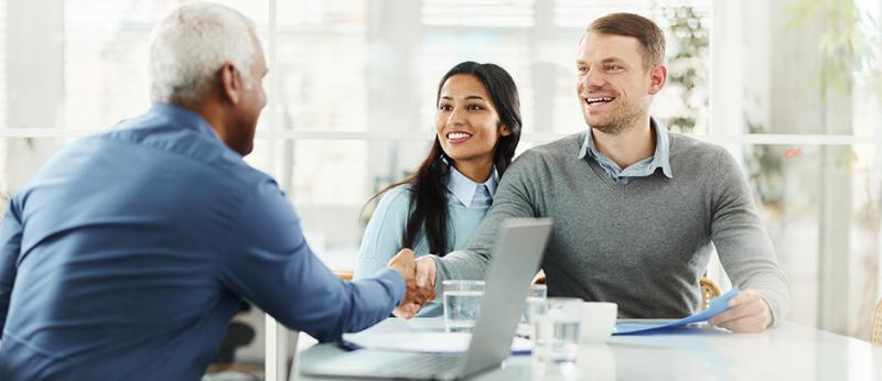 Real Estate agent shaking hands with young sellers couple