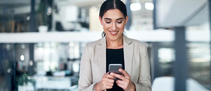 Business woman smiling while looking at her smartphone