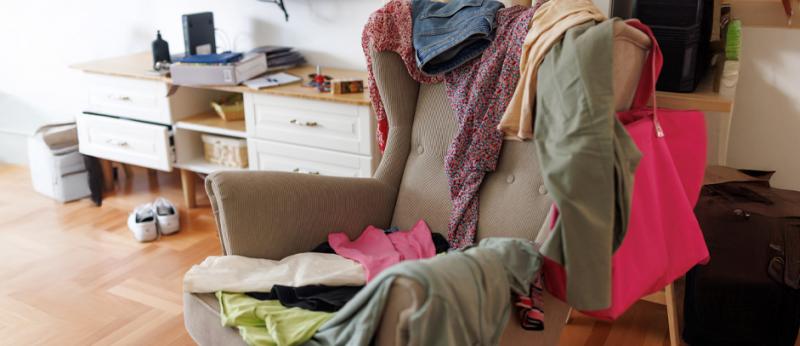Messy room with scattered clothes on the armchair without people