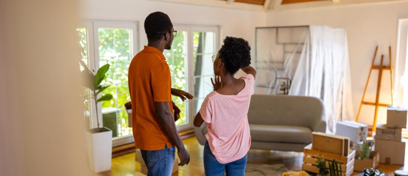 Two people, happy young black couple standing in their new apartment.