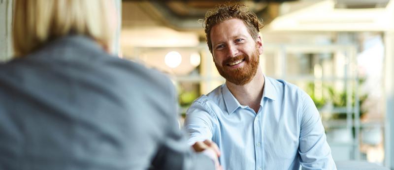 Business man reaching to shake the hand of another colleague