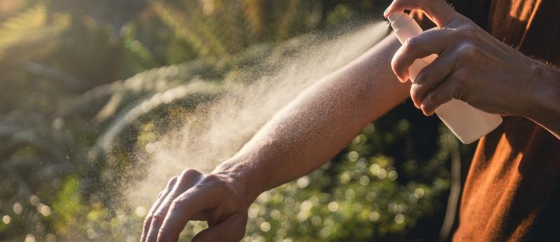Man while applying insect repellent on his arm. Prevention against mosquito bite in tropical destination