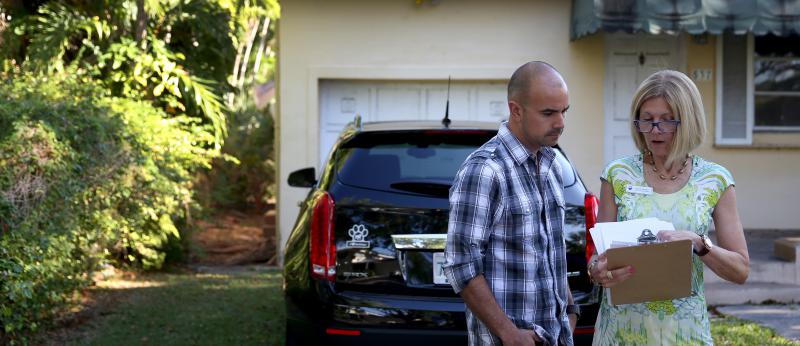 Realtor reviewing paperwork with a client outside a home