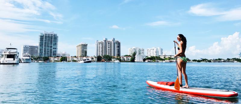woman paddleboarding with florida skyline in background