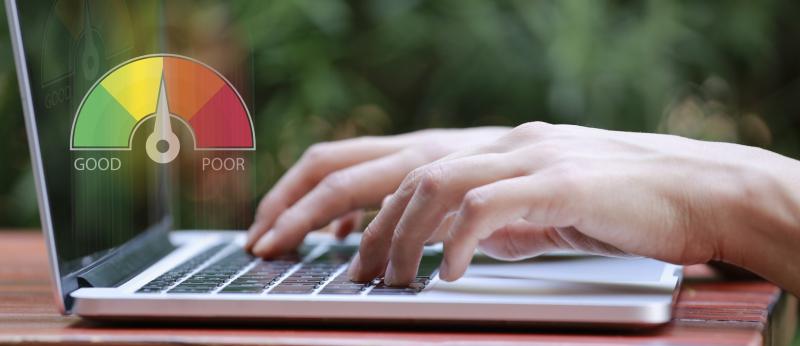 hands typing on laptop with credit score meter