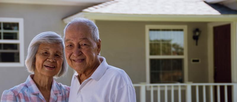 older couple standing outside house