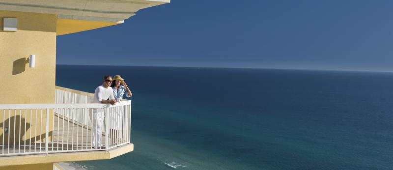 Couple stands on balcony overlooking the ocean