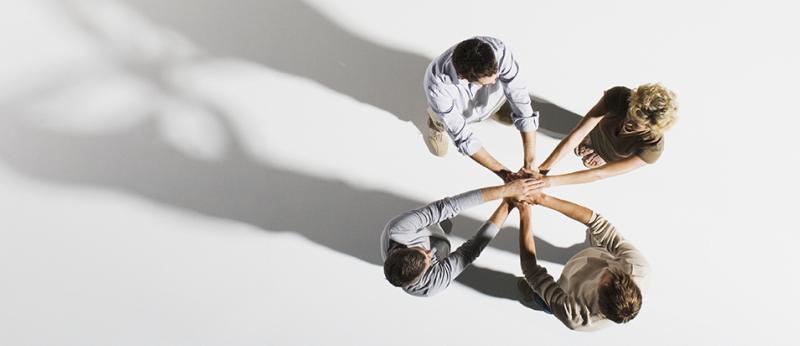 four people with hands on top of each others