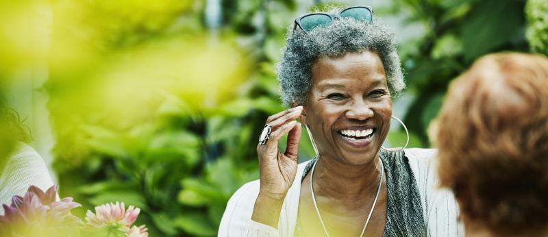Older woman smiling while outdoors talking to another woman
