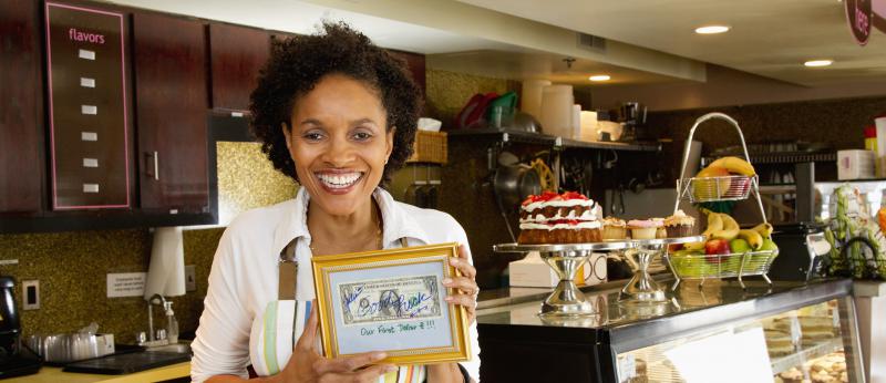 Bakery owner holding first dollar earned
