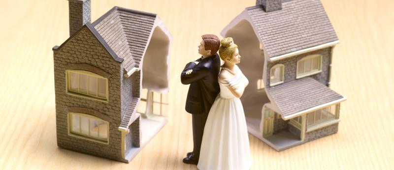 Cake topper couple back to back with two toy homes in background