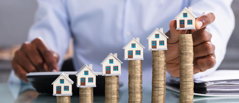 Higher and higher stacks of coins with small houses on top