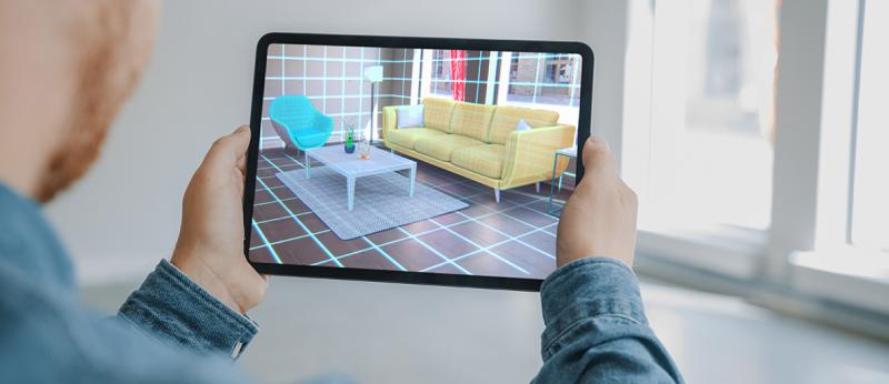 Photo of a man looking at a virtual rendering of a living room on his tablet
