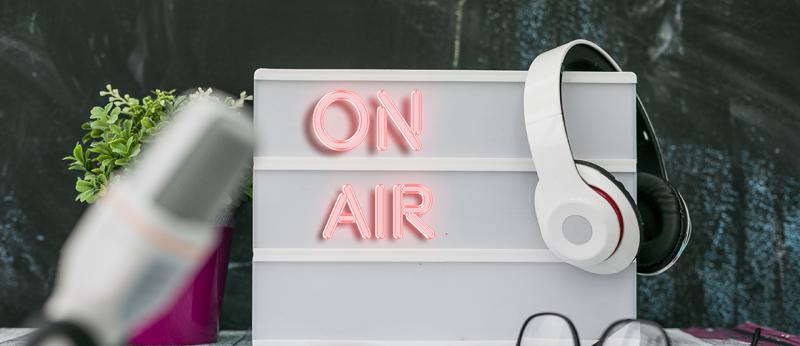 Photo of a sign that says On Air with headphones hanging on it.