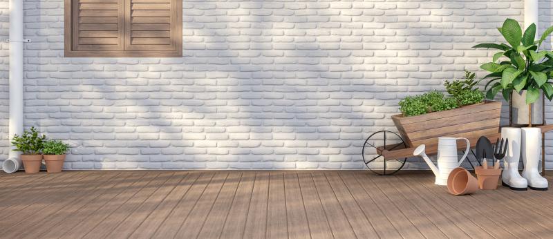Home with white painted brick with a brown window and plants along the side