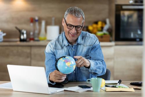 Man at desktop with laptop holding globe