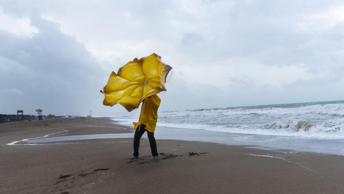 Man with umbrella on beach during storm