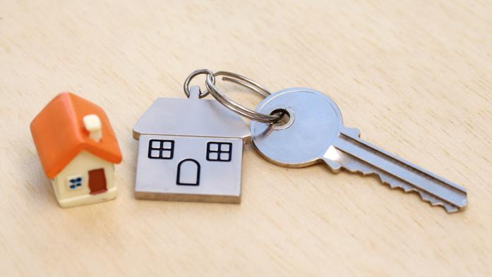 close up of small house beside metal house keychain and key