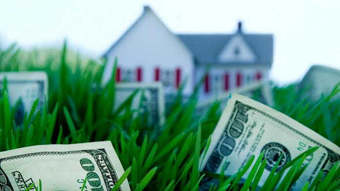 Photo illustration of a house nestled in grass and money