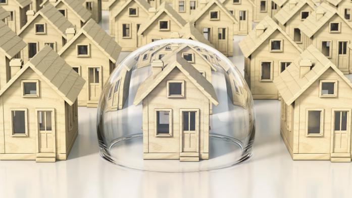 Small models of homes; the center one is covered in a bubble