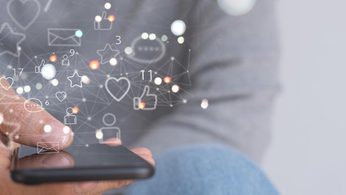 Photo of a person holding a phone with social media icons