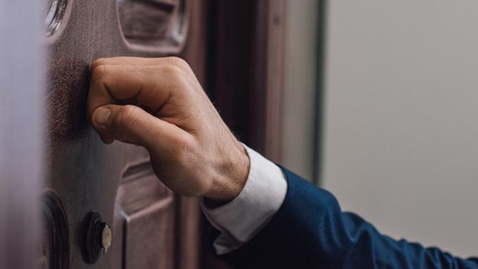 Photo of hand knocking on front door