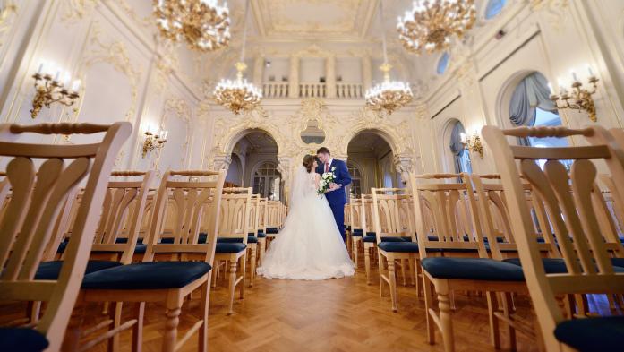 A bride and groom embrace in the aisle of a lavish church