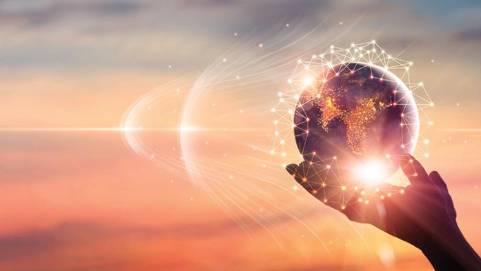 Photo of a hand holding a globe with rays of light emanating from it