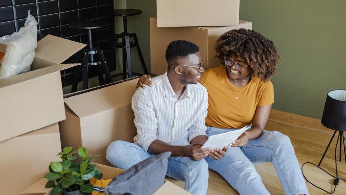 Happy renters look over their rental agreement surrounded by boxes