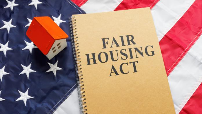 fair housing act on notebook near tiny house on American flag