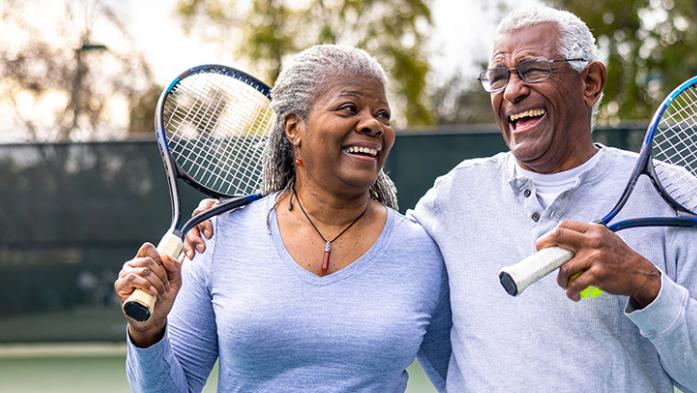 Photo of a mature African American man and woman holding tennis rackets