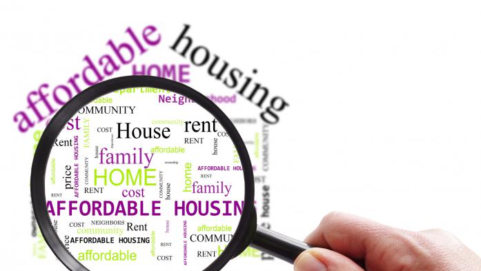 hand with magnifying glass over affordable housing word cloud