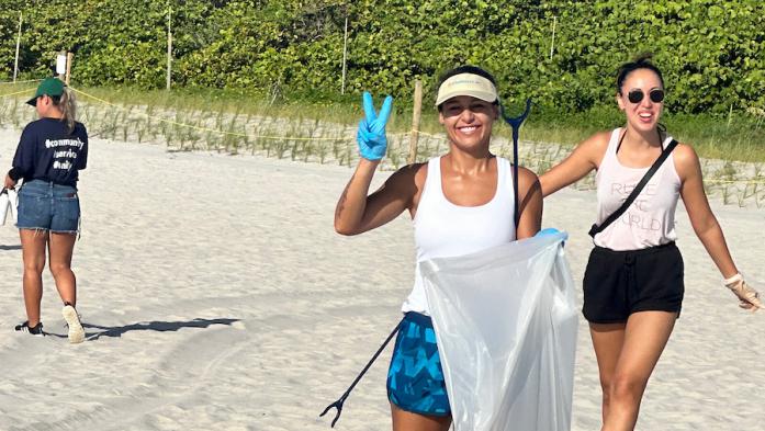 Two women on beach cleaning up trash