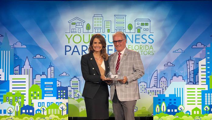 two people holding award on a stage