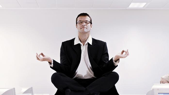 Photo of a business man sitting on a desk meditating