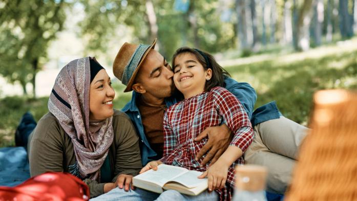 Muslim family with one child sitting outside reading