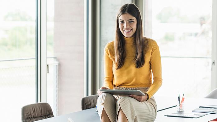 Photo of Millennial Realtor sitting on a desk using a tablet computer