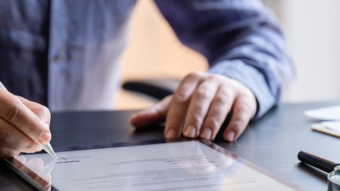 Photo of a man signing a contract on a tablet computer