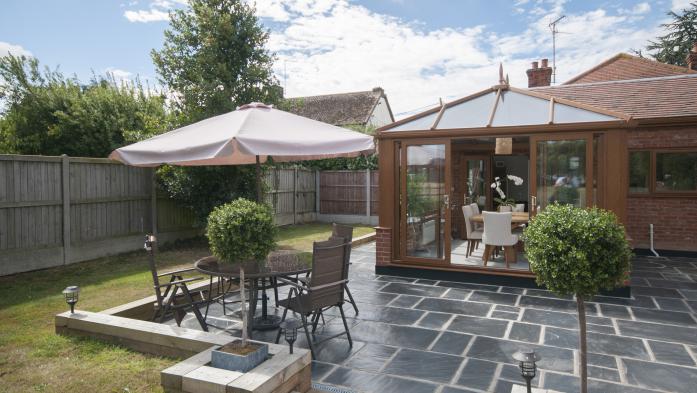 Small ADU home sits along a slate patio with table and chairs nearby