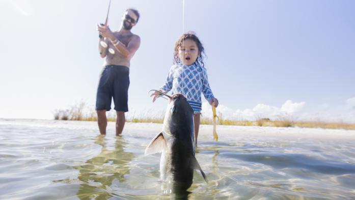 Toddler stares in amazement as father catches a fish