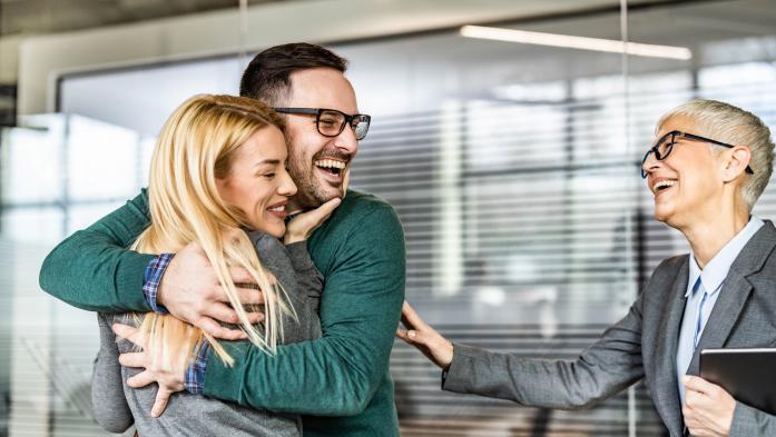 couple hugging and smiling while older woman looks on, smiling.