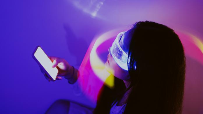photo illustration of woman holding cell phone with light wrapped around her face and eyes