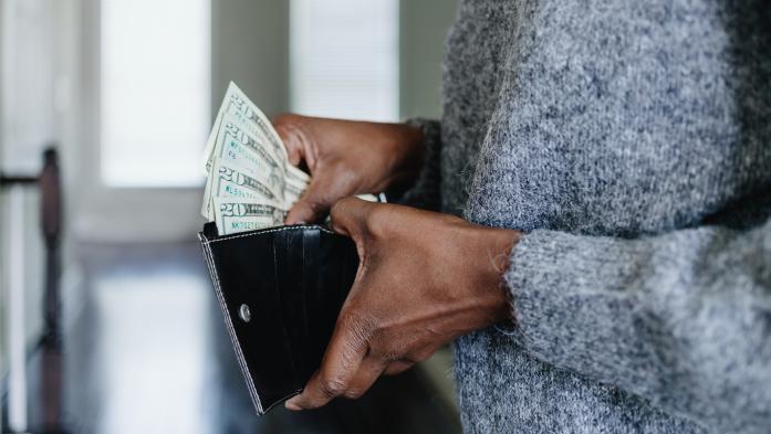 hands holding wallet filled with cash