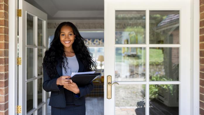 young female woman holding paperwork standing in open french door